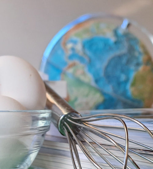 En bild fotad i Slussens klassrum. I förgrunden ser man en glasskål med ägg, en ballongvispel och en hög skolböcker. I bakgrunden ser man en pennburk och en jordglob.