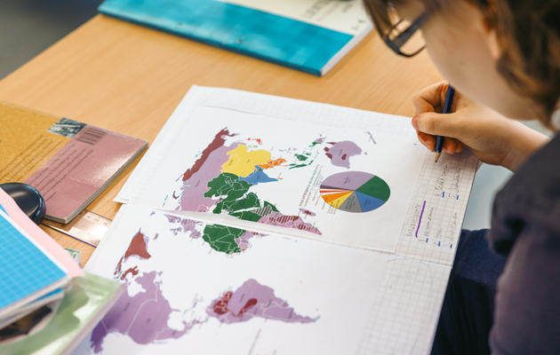 Närbild av skolbok. På uppsalget ser man världskartan.